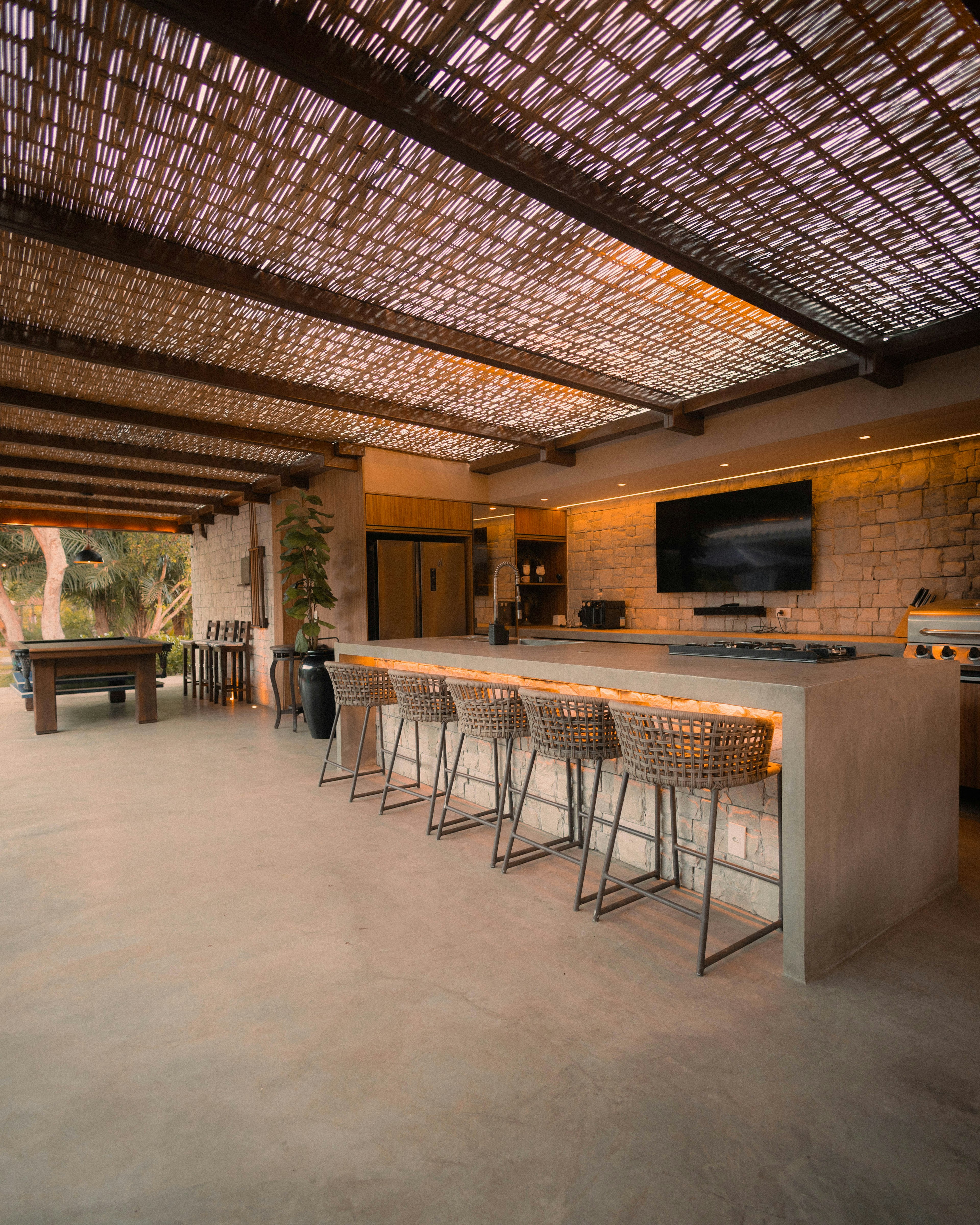 Cozinha exterior com ilha e bancos de bar